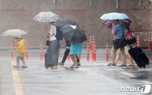 장마가 시작된 26일 오전 제주시 제주국제공항 앞 건널목에서 공항 이용객들이 우산을 쓰고 발걸음을 재촉하고 있다.2019.6.26/뉴스1 © News1