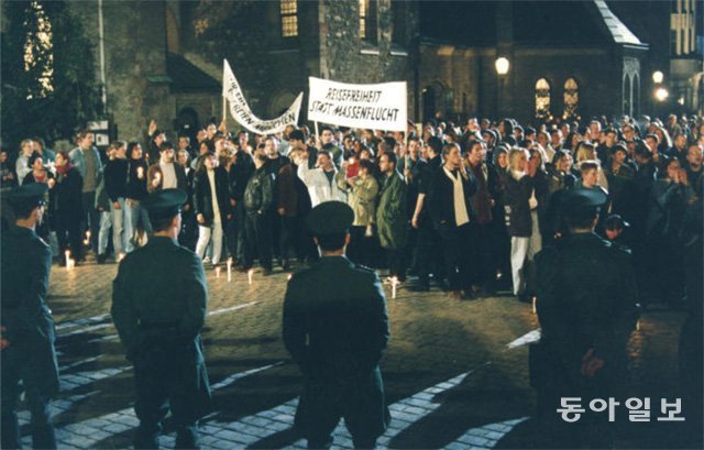 1989년 10월 독일 라이프치히 성니콜라이교회 앞에 모인 시위대가 개혁과 개방을 외치며 촛불을 앞에 놓고 슈타지 요원들과 대치하고 있다. 동아일보DB