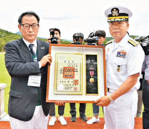6·25전쟁 당시 민간인 신분으로 참전했다 전사한 문산호 선원 고 이수용 씨의 아들 이용규 씨(왼쪽)가 27일 충남 계룡대 해군 본부에서 심승섭 해군참모총장으로부터 훈장을 전달받고 있다. 해군 제공