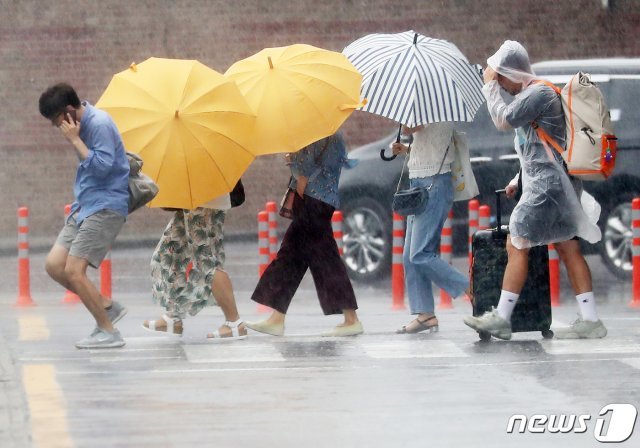 장마가 시작된 지난 26일 오전 제주시 제주국제공항 앞 건널목에서 공항 이용객들이 우산을 쓰고 발걸음을 재촉하고 있다. © News1