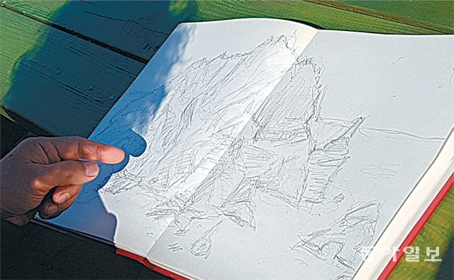 김 화백은 스케치를 보여 달라는 일행의 거듭된 채근에 스케치북을 펼치며 “이 스케치를 바탕으로 하되 굵은 선의 모필 작품으로 서도를 형상화할 생각”이라고 말했다(왼쪽 사진). 독도=유윤종 기자 gustav@donga.com