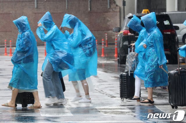 장마가 시작된 26일 오전 제주시 제주국제공항 앞 건널목에서 공항 이용객들이 우비를 입고 발걸음을 재촉하고 있다. © News1