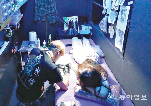 4일 오후 서울 지하철 2호선 홍대입구역 인근 타투숍에서 문신사(왼쪽)가 여성 손님의 팔에 문신을 새기고 있다. 홍대입구역 인근에만 20곳이 넘는 타투숍이 몰려 있다. 김재명 기자 base@donga.com
