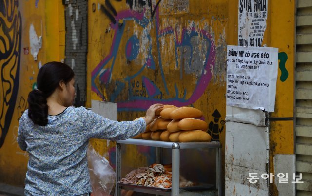 한 여성이 베트남식 샌드위치인 반미를 팔기 위해 빵을 준비하고 있습니다.