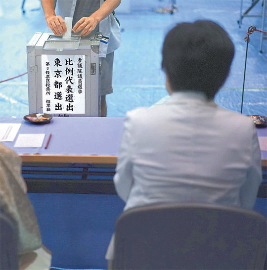 일본 참의원 선거가 열린 21일 도쿄에 마련된 투표소를 찾아온 한 유권자가 선거관리위원들이 지켜보는 가운데 기표를 마친 투표용지를 접어 투표함에 넣고 있다. 지원 유세 기간 아베 신조 일본 총리는 ＂이번 선거가 끝나면 반드시 헌법에 ‘자위대‘를 명기하겠다＂는 공약을 내건 바 있다. 도쿄=AP 뉴시스
