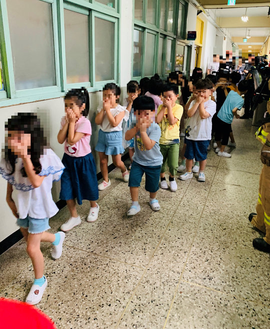 25일 포름알데히드 희석액(포르말린) 유출 사고가 발생한 서울 구로구 구일초등학교 학생들이 양손으로 입과 코를 막은 채 대피하고 있다. 서울 구로소방서 제공