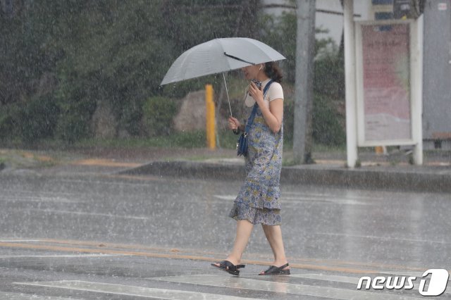 중부지방에 장마가 이어진 25일 오후 경기도 수원시 장안구 거리에서 한 시민이 우산을 쓴 채 발걸음을 재촉하고 있다. 기상청 예보에 따르면 28일까지 100㎜~250㎜의 비가 올 것으로 보이며, 많은 곳의 경우 400㎜ 이상의 폭우가 쏟아질 예정이다. 2019.7.25/뉴스1 © News1