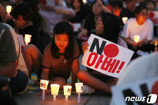 지난달 27일 오후 서울 종로구 광화문광장에서 열린 ‘역사왜곡, 경제침략, 평화위협 아베 규탄 2차 촛불문화제’에서 어린들이 일본 아베 정권을 규탄하는 내용을 담은 촛불을 밝히고 있다. 뉴스1 © News1