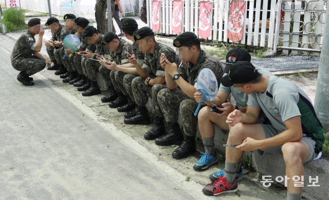 1일 오후 2시경 강원 화천군 토마토축제 현장을 찾은 군 병사 10여명이 보도블럭에 앉아 휴대폰을 사용하고있다.