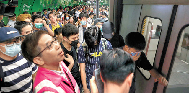 지하철 ‘게릴라 시위’ 5일 ‘범죄인 인도 법안’에 반대하는 시민들의 주도로 대규모 총파업이 벌어진 홍콩에서 마스크를 쓴 시위대가 홍콩 지하철(MTR)의 운행을 방해하고 있다. 20개 산업에서 50만 명 이상의 시민들이 동참한 이번 시위로 열차 운행이 금지되고 도로가 점거돼 홍콩 시내 곳곳이 마비됐다. 홍콩=AP 뉴시스
