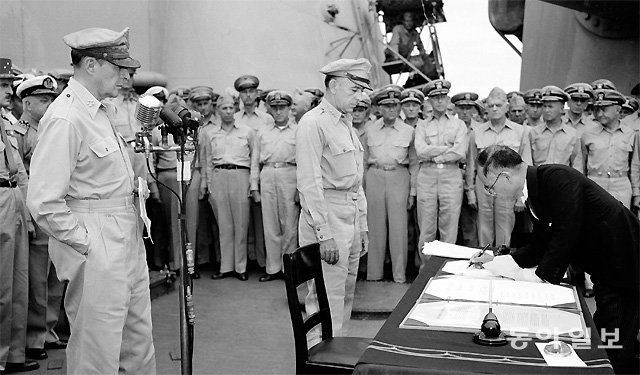 태평양전쟁에서 패전한 뒤 1945년 9월 2일 일본 도쿄만에 정박한 미군 전함 미주리호 위에서 항복 문서에 서명하는 시게미쓰 마모루 일본 외무대신. 맥아더 장군(왼쪽 마이크 앞 인물)과 미군 장병들이 지켜보고 있다. 동아일보DB