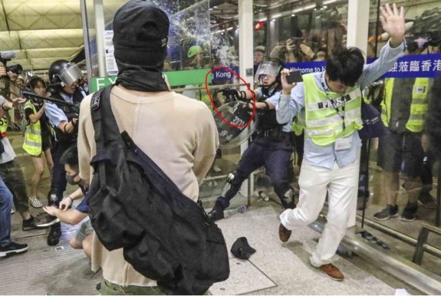 한 홍콩 경찰이 공항 시위 진압 도중 권총으로 시위대를 위협하고 있다. SCMP 갈무리