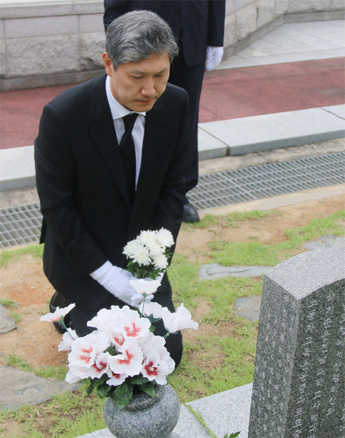 노태우 전 대통령의 아들 재헌 씨가 23일 광주 국립5·18민주묘지 윤상원 열사 묘역 앞에서 두 손으로 꽃을 들고 무릎 
꿇고 앉아 오월 영령을 추모하고 있다. 국립5·18민주묘지관리소 제공