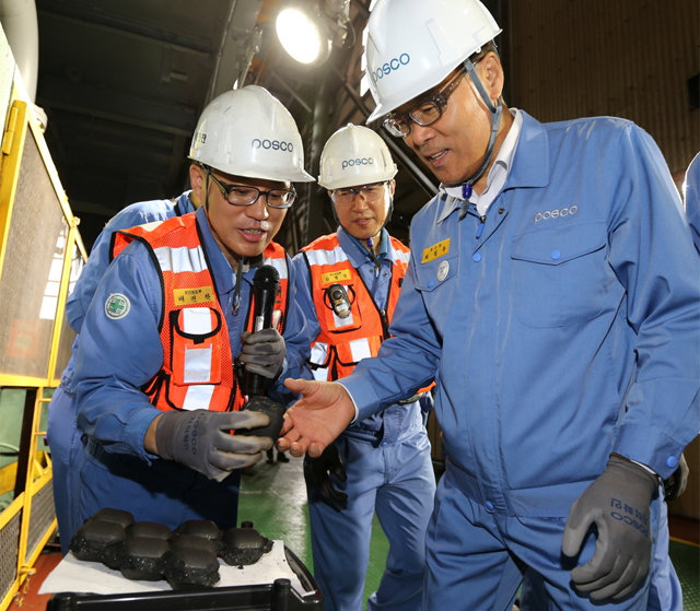 최정우 포스코 회장(오른쪽)이 27일 경북 포항제철소 ‘파이넥스 성형탄 공장’을 방문해 현장 직원들과 생산된 성형탄 제품을 살펴보고 있다. 포스코 제공