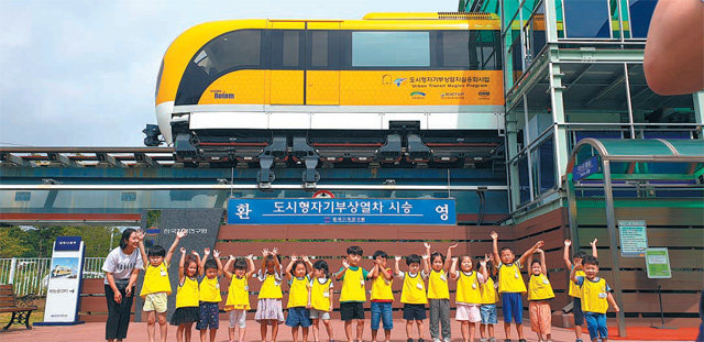 어린이들이 한국기계연구원에서 레일 위를 달리는 자기부상열차 앞에서 환하게 웃고 있다. 한국기계연구원 제공