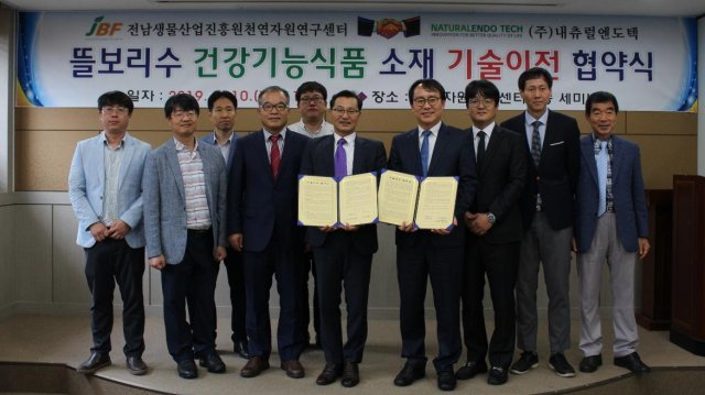 이학성 전남생물산업진흥원 천연자원연구센터장(왼쪽부터 6번째)과 이용욱 내츄럴엔도텍 대표이사(7번째)를 비롯한 관계자들이 기술이전 협약을 체결한 후 기념촬영을 하고 있다. 사진제공｜내츄럴엔도텍
