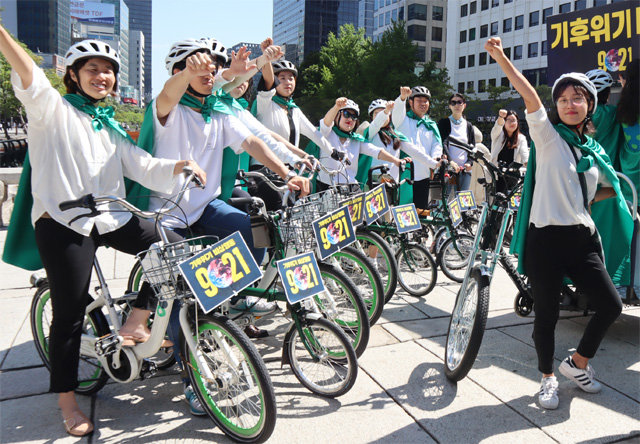 21일 열리는 ‘기후위기 비상행동’ 집회를 알리기 위해 18일 환경운동연합 회원들이 ‘자전거를 탄 초록 슈퍼맨’으로 분해 서울 청계천에 모였다. 환경운동연합 제공