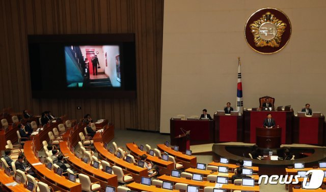 김철민 더불어민주당 의원이 26일 서울 여의도 국회 본회의장에서 열린 정기국회에서 조국 법무부장관에게 정치분야 대정부 질의를 하고 있다. 조국 장관이 케이크를 들고 아파트 승강기 앞에 서 있는 사진이 전광판에 게시되었다. 2019.9.26/뉴스1 © News1