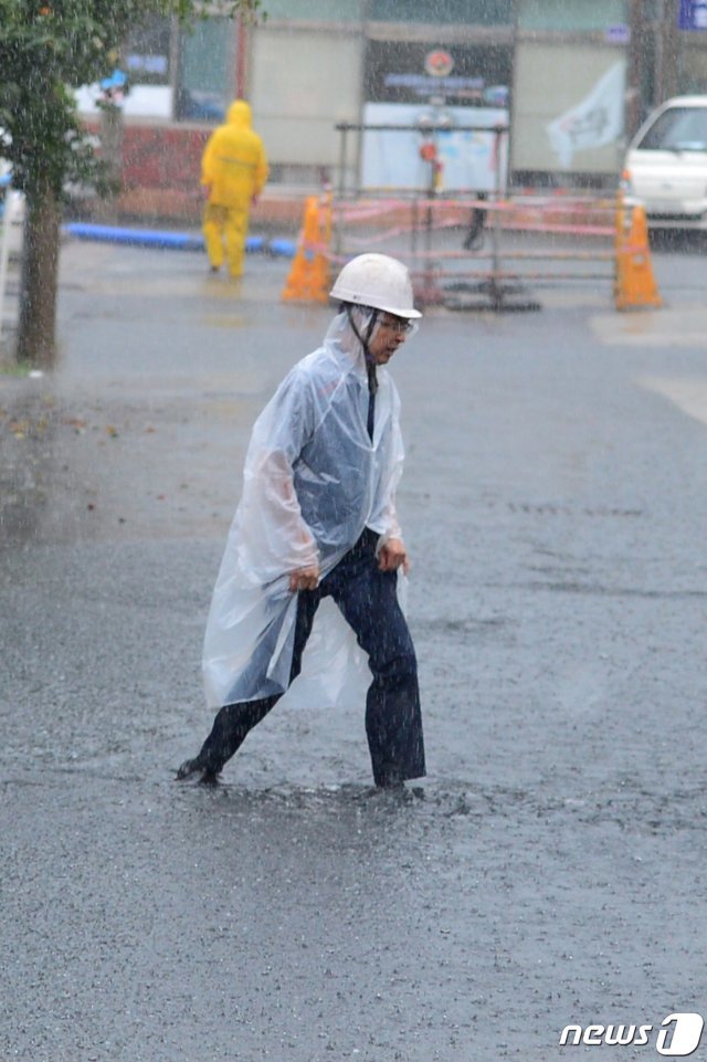 북상 중인 태풍 미탁 간접영향권에 들어간 2일 오후 경북 포항시 북구 장성동 장성시장 앞 도로가 폭우에 침수되자 배수펌프를 작동하기 위해 나온 공무원이 힘겹게 걸어가고 있다. 2019.10.2/뉴스1 © News1