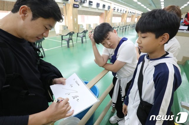 5일 오전 대구사격장에서 열린 제100회 전국체육대회 사격 남자일반부 권총 50m에 출전한 서울 진종오가 합계 558점으로 6위를 기록하며 경기를 마친 뒤 어린이 팬에게 사인을 해주고 있다. 2019.10.5/뉴스1 © News1