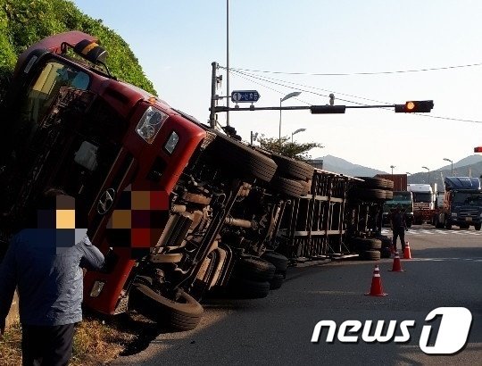 8일 오후 4시5분쯤 부산 강서구에 있는 부산신항 1번 교차로에서 가주터널 방향으로 목재 약 20톤을 싣고 주행하던 대형 트레일러가 오른쪽으로 넘어졌다. 트레일러가 넘어져 도로를 가로막은 모습.(부산지방경찰청 제공)© 뉴스1