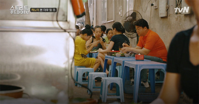 지난달 29일 tvN ‘스트리트 푸드 파이터2’ 하노이 편에서 백종원 씨가 현지인들과 뒤섞여 얇은 쌀국수와 튀긴 두부가 담긴 요리 ‘분더우맘똠’을 먹는 장면. tvN 제공