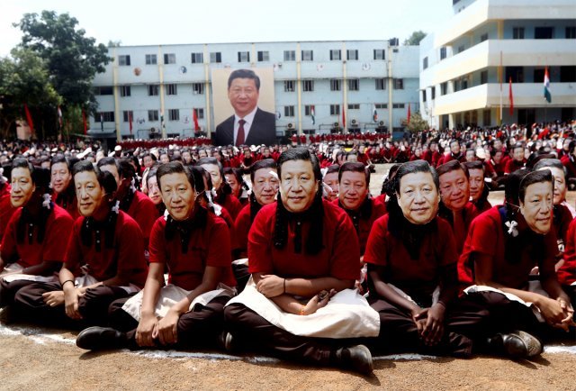 10일 인도 첸나이의 한 학교에서 인도 학생들이 시진핑 중국 국가주석의 얼굴 사진으로 만든 가면을 쓴 채 앉아 있다. 학생들 뒤로
 시 주석의 대형 초상화가 걸려 있다. 이날 이 학교 학생 2000명은 시 주석의 방문을 환영하기 위해 이 행사를 열었다. 
첸나이=AP 뉴시스