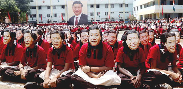 10일 인도 첸나이의 한 학교에서 인도 학생들이 시진핑 중국 국가주석의 얼굴 사진으로 만든 가면을 쓴 채 앉아 
있다. 학생들 뒤로 시 주석의 대형 초상화가 걸려 있다. 이날 이 학교 학생 2000명은 시 주석의 방문을 환영하기 위해 이 
행사를 열었다. 첸나이=AP 뉴시스