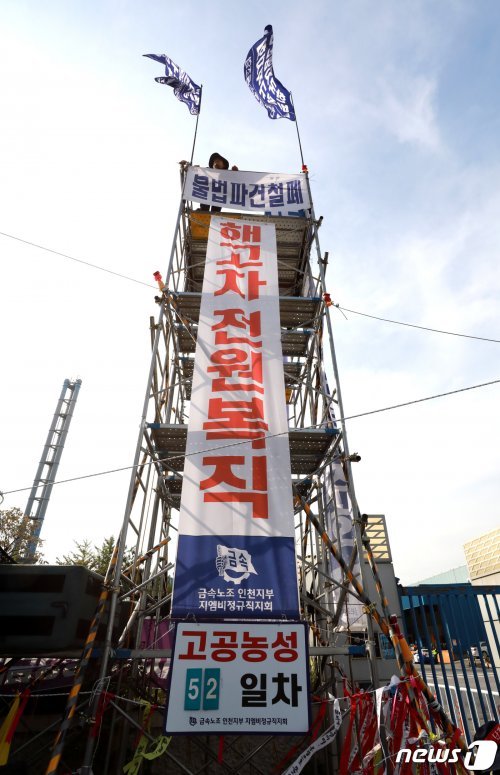 16일 오후 인천시 부평구 한국지엠 정문앞에서 ‘한국GM 자본규탄 민주노총 결의대회’가 열리고 있는 가운데 한 노동자가 철탑위에서 고공농성을 하고 있다. 2019.10.16/뉴스1 © News1 정