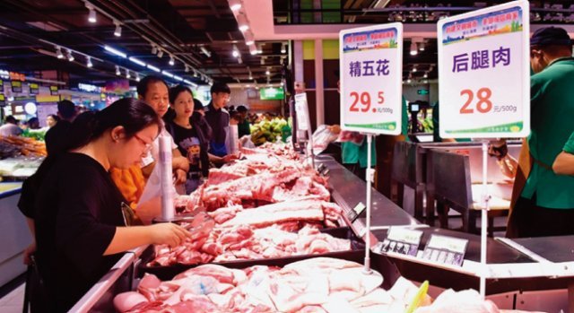 중국인 주부가 시장 정육점에서 돼지고기를 살펴보고 있다. [VCG]