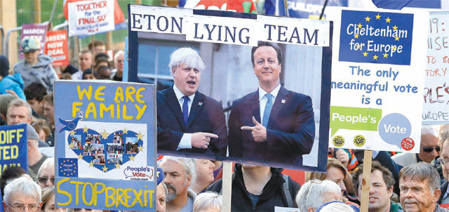 “거짓말쟁이” 전현직 총리 비꼰 시위대 19일 영국 런던 의사당 인근에서 영국의 유럽연합(EU) 탈퇴(브렉시트)에 반대하는 시민들이 ‘제2의 국민투표’를 요구하는 시위를 열고 있다. 한 시위 참가자가 보리스 존슨 영국 총리와 데이비드 캐머런 전 총리의 사진과 함께 이들의 출신 학교인 이튼스쿨을 언급하며 ‘거짓말쟁이 이튼 팀’이란 문구를 담은 플래카드를 들고 있다. 이날 영국 하원은 영국 정부와 EU가 마련한 새 브렉시트 합의안의 의회 승인을 전격 보류했다. 런던=AP 뉴시스