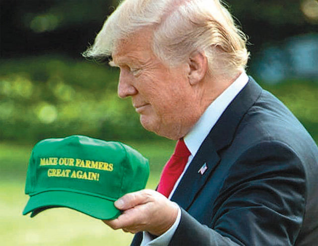 도널드 트럼프 미국 대통령이 ‘우리 농민들을 다시 위대하게’라는 글자가 새겨진 모자를 제작해 기자들에게 자랑하고 있다. 그러나 요즘에는 농민들의
반발로 모자를 거의 쓰고 다니지 않는다. 액시오스 웹사이트