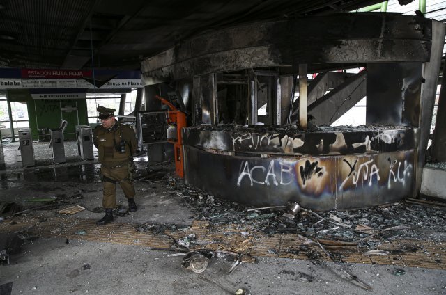 지난 19일 칠레 산티아고에서 경찰관이 전날 시위대에 의해서 불에 탄 지하철 역 내를 순찰하고 있다. [산티아고=AP/뉴시스]