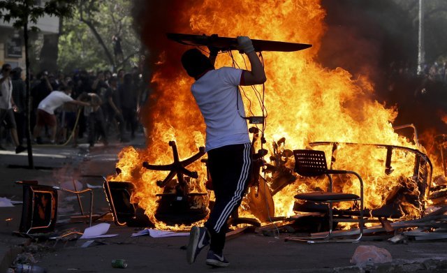 지난 21일 산티아고에서 시위대들이 집기들을 거리에 불태우며 행진하고 있다. [산티아고=AP/뉴시스]