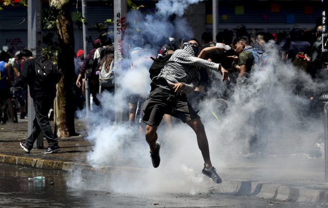 지난 21일 산티아고에서 열린 집회에서 한 시위대가 경찰이 던진 최루탄을 되던지고 있다.[산티아고=AP/뉴시스]
