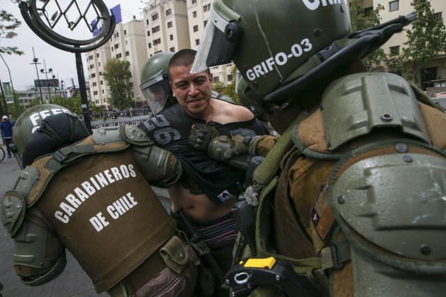 지난 19일 칠레 산티아고에서 열린 집회에서 한 시위대가 군인에 의해 제압당하고 있다. [산티아고=AP/뉴시스]