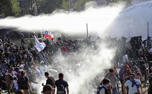 지난 20일 경찰이 쏜 물대포에 칠레 시위대들이 흩어지고 있다. [산티아고=AP/뉴시스]