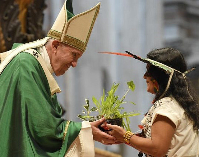 프란치스코 교황(왼쪽)이 27일(현지 시간) 바티칸 교황청에서 진행된 세계주교대의원회의(시노드) 폐막 미사에서 아마존 원주민 여성에게 초록 식물을 건네고 있다. 바티칸뉴스 웹사이트