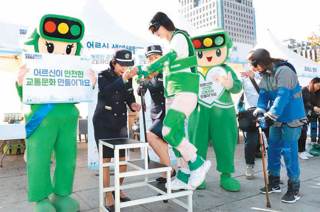 1일 서울 광화문광장에서 열린 ‘2019 어르신 교통사고 제로 캠페인’ 행사에서 참여자들이 고글과 모래주머니 등을 착용한 채 경찰의 도움을 받아 ‘어르신 보행’ 체험을 하고 있다. 뉴시스