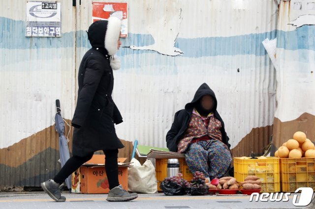 13일 오전 경기 수원시내 한 거리에서 노점상인이 추위를 견디기 위해 두꺼운 옷을 입고 손님을 기다리고 있다. 2019.11.13/뉴스1 © News1