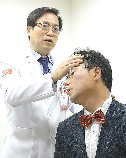 에이치플러스 양지병원 최창명 신경외과 과장이 본보 이진한 기자에게 목을 왼쪽과 오른쪽으로 비틀어 통증 여부를 알아보는 스펄링 검사를 하고 있다.