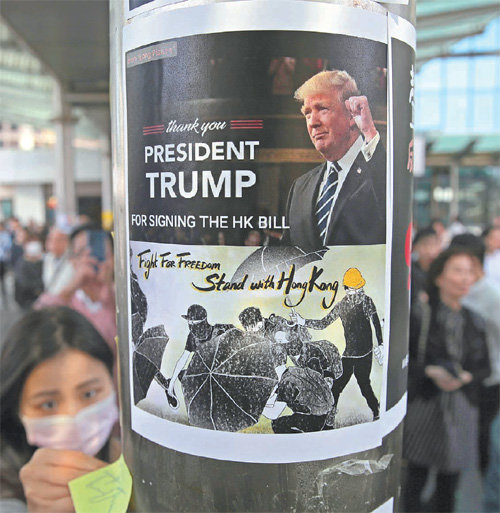 홍콩 시위대 “고마워요 트럼프” 28일 홍콩 반중 시위대원 1명이 도심 금융지구의 건물 기둥 벽면에 도널드 트럼프 미국 대통령이 등장한 게시물을 붙이고 있다. 트럼프 대통령은 전날 중국의 강력한 반발에도 홍콩인권법안에 서명하며 시위대를 지지할 뜻을 밝혔다. 홍콩=AP 뉴시스