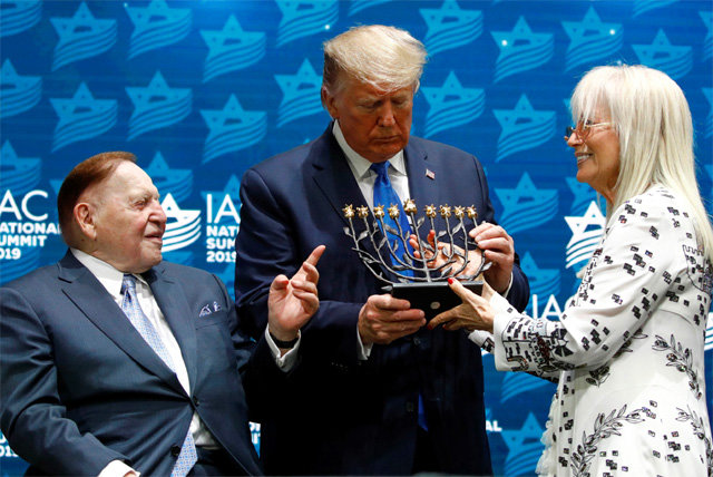 7일 미국 할리우드에서 열린 유대계 미국인협의회 전국 회의에서 도널드 트럼프 미국 대통령(가운데)이 셸던 애덜슨 라스베이거스 샌즈 그룹 회장(왼쪽) 부부로부터 이스라엘의 상징인 ‘메노라(촛대)’를 받았다. 할리우드=AP 뉴시스