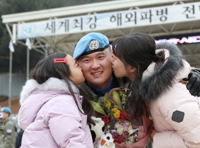 파병장병의 부인과 딸이 볼에 키스를 하고있다.