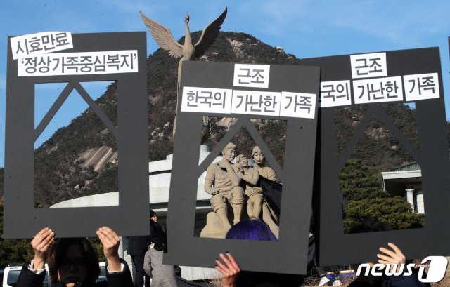 19일 오후 서울 종로구 청와대 앞 분수대 광장에서 열린 ‘부양의무자기준 폐지를 위한 청와대 농성 마무리 기자회견’에서 참가자들이 분수대 가족상(像)에 검은 천을 두르는 퍼포먼스를 하고 있다. 2019.12.19/뉴스1 © News1