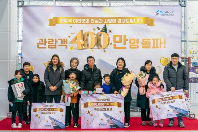 국립부산과학관 고현숙 관장(왼쪽 다섯 번째)이 400만 번째 및 전후 방문 관람객과 기념촬영을 하고 있다.