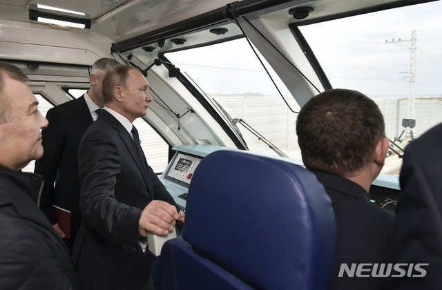 블라디미르 푸틴 러시아 대통령이 23일(현지시간) 크림반도와 러시아 본토를 연결하는 케르치 철교를 개통하면서 3량짜리 특별 열차에
 시승하고 있다. 푸틴 대통령은 러시아가 2014년 우크라이나에서 합병한 크림반도와의 연결을 쉽게 하기 위해 만든 유럽에서 가장 긴
 길이 19km의 케르치 철교 개통식에 참석했다. ﻿[케르치=AP/뉴시스]