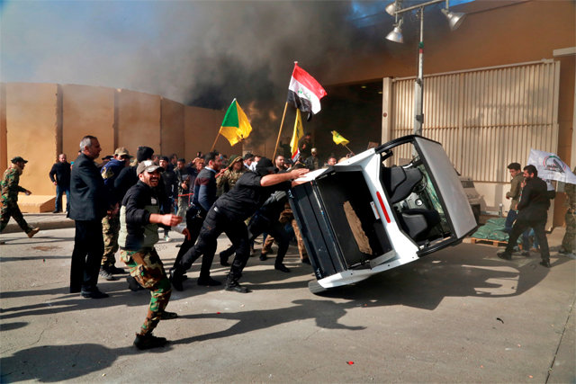 사상 최초 공격받은 이라크 美대사관 지난해 12월 31일 이라크 수도 바그다드의 친이란 시위대가 미국대사관 앞에 있는 차량을 넘어뜨리며 내부 진입을 시도하고 있다. 시위대가 대사관 외벽에 불을 질러 이들의 뒤로 검은 연기가 피어오르고 있다. 시위대는 미국이 이틀 전 이란의 지원을 받는 시아파 민병대 ‘카타입헤즈볼라(KH)’를 공격한 것이 주권 침해라며 대사관 진입을 시도했다. 바그다드=AP 뉴시스