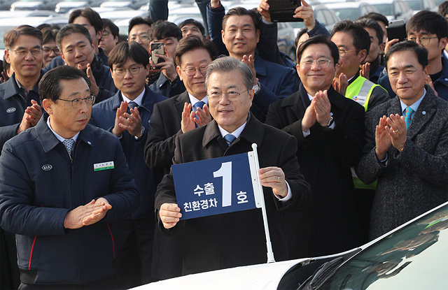 문재인 대통령이 새해 첫 경제 행보로 3일 경기 평택항을 찾아 올해 처음 수출되는 기아자동차의 친환경차 ‘니로’에 ‘수출 
1호 친환경차’라는 깃발을 꽂고 있다. 문 대통령은 “2025년까지 기술 개발에 3800억 원 이상을 투자해 세계 최고의 친환경차
 개발을 도울 것”이라고 했다. 평택=청와대사진기자단