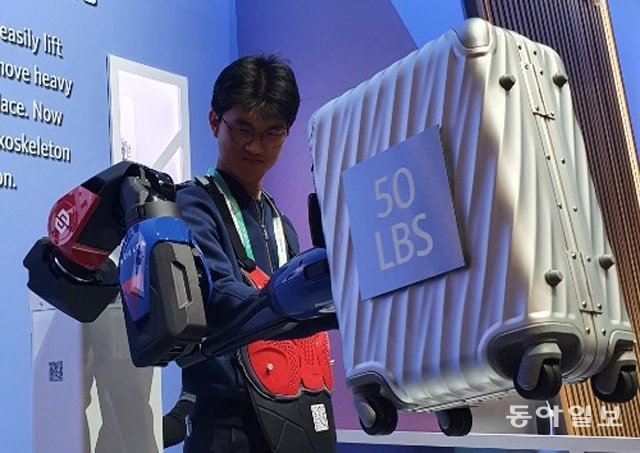 본보 김도형 기자가 델타의 보조 로봇을 착용하고 50파운드(약 23kg) 무게의 짐을 한 손으로 가뿐히 들어올리고 있다. 라스베이거스=곽도영 기자 now@donga.com